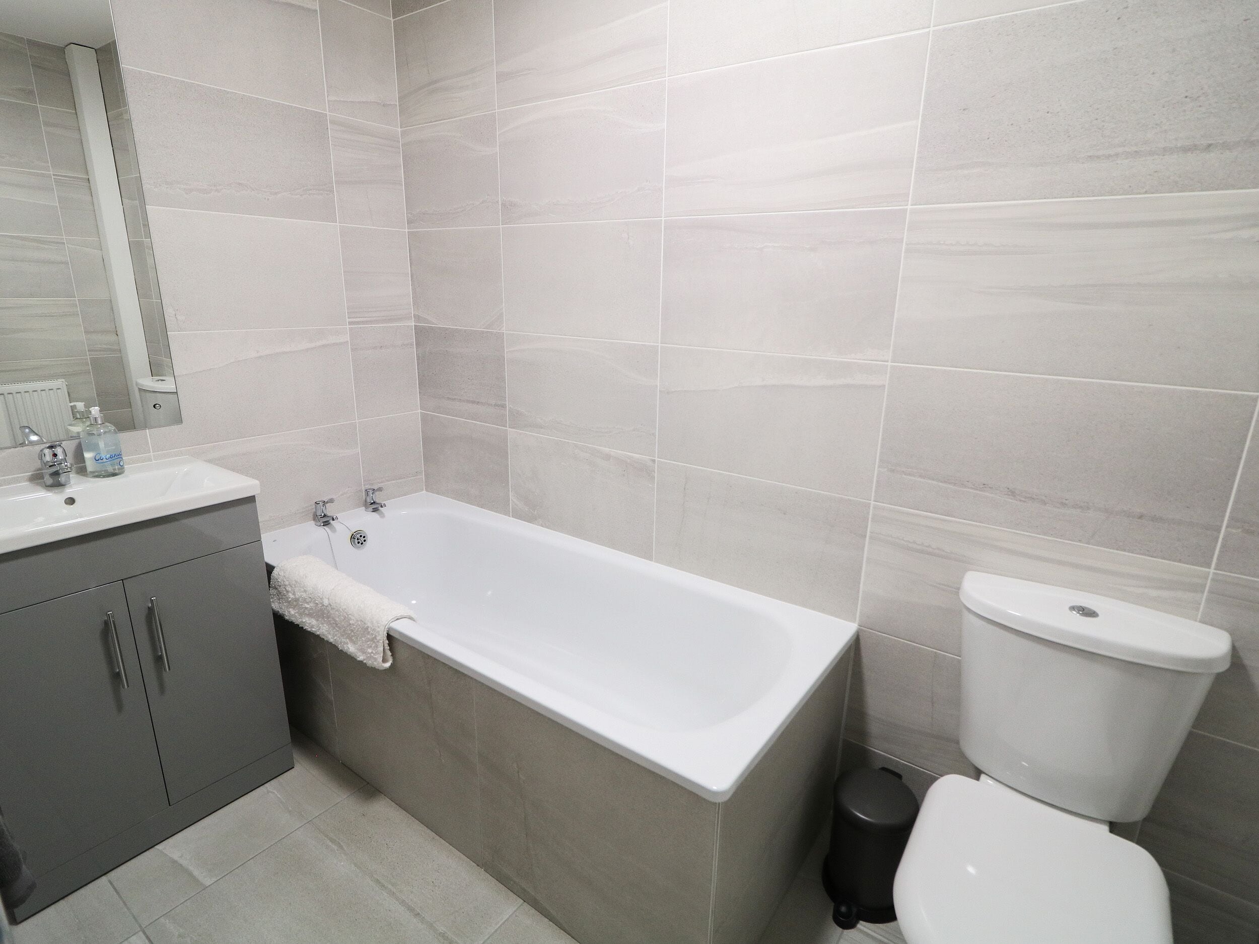 Un baño con bañera, inodoro y tocador con espejo.