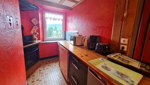 A compact kitchen with a window, a toaster, a coffee maker, and a refrigerator.