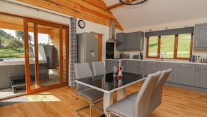 A modern kitchen with grey cabinets, a dining table with chairs, and a large window offering a view of the outdoors.