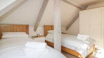 Ein Schlafzimmer mit zwei Betten, Holz-Kopfteilen, weißer Bettwäsche und einem Kleiderschrank.