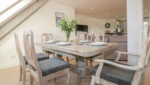Comedor con una mesa de madera dispuesta para seis personas, rodeada por seis sillas con asientos acolchados.