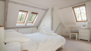 Un dormitorio con cama, escritorio y dos ventanas.