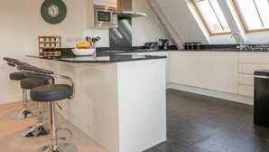 Una cocina moderna con una isla central, taburetes de bar, microondas y cafetera.