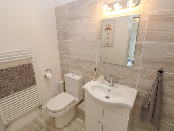 A bathroom with a toilet, sink, and mirror.