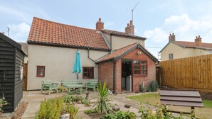 Une maison à deux étages, avec un toit en tuiles, une façade en briques et un petit garage attenant.