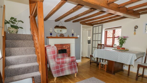 Un escalier avec des marches recouvertes de moquette, un fauteuil à carreaux, une table à manger avec des chaises et une cheminée.