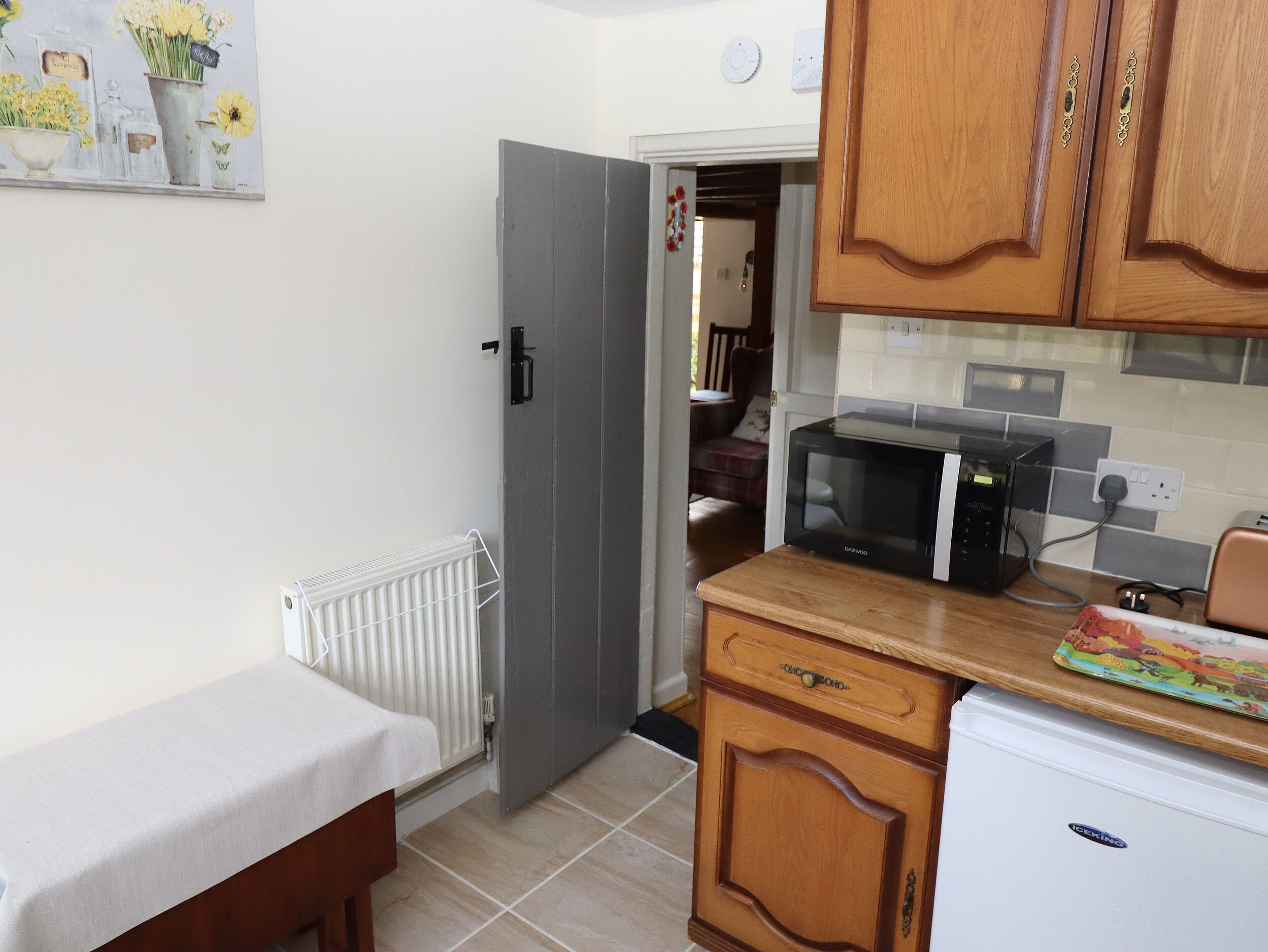 A compact kitchen with a microwave, a refrigerator, and wooden cabinets.