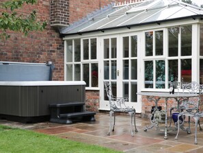 Un invernadero con techo de cristal, jacuzzi y mobiliario exterior.