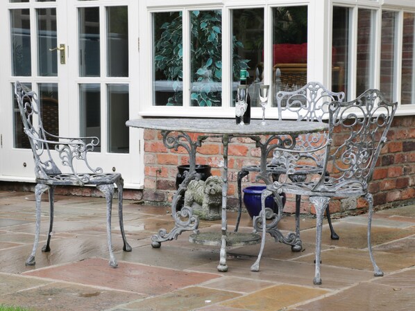 Une terrasse extérieure avec une table ronde et deux chaises en métal décorées.