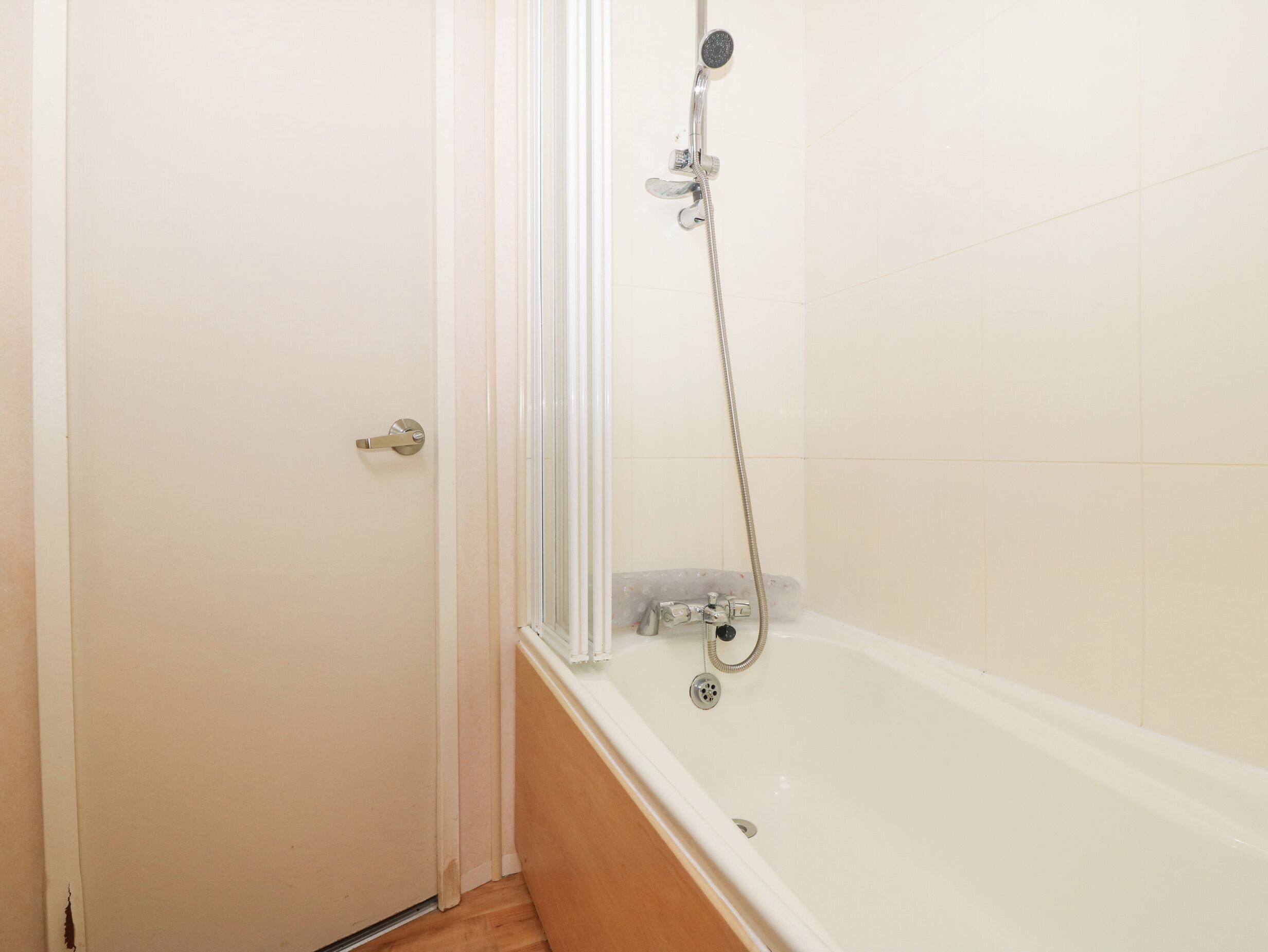 A bathroom with a shower, a bathtub, and a door.