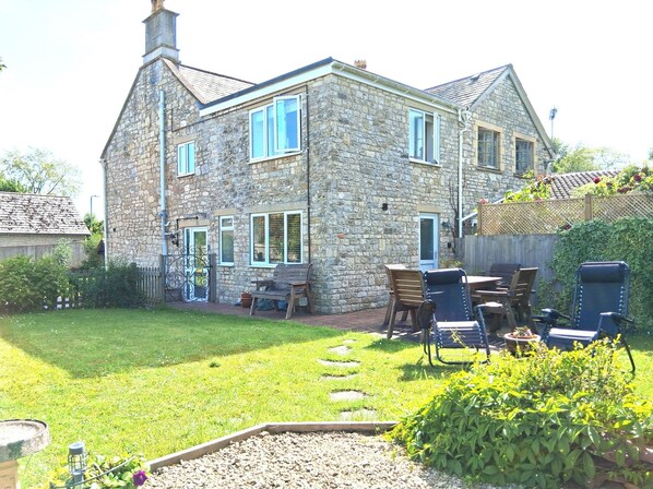 A stone house with a garden, outdoor seating, and a visible door.