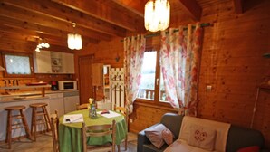 A cozy cabin interior with a dining area, kitchen, and living space. - Cozy Chalet near Plombières-les-Bains - Ideal for Couples, Nature Trails, and Relaxing Spa Retreat (Le Val-d'Ajol)