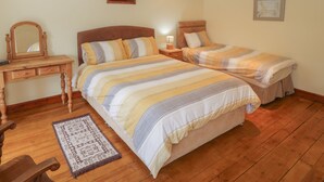A bedroom with two beds, a wooden dresser, a mirror, and a rug. - Bron Gadair (Llanfairpwllgwyngyll)