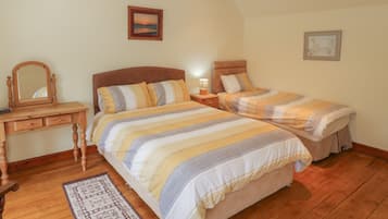 A bedroom with two beds, a wooden dresser, a mirror, and a rug.
