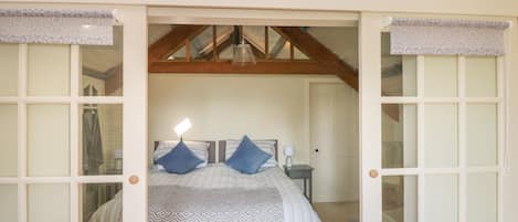 A bedroom with a bed, a nightstand, and a window.