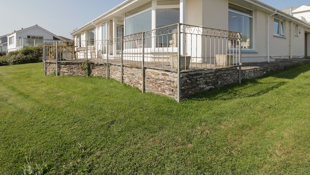 Une maison moderne dotée d’une grande baie vitrée, de fondations en pierre et d’une façade blanche.