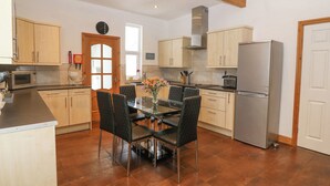 Una cocina moderna con armarios de madera, un refrigerador de acero inoxidable, un microondas y una mesa de comedor con sillas.