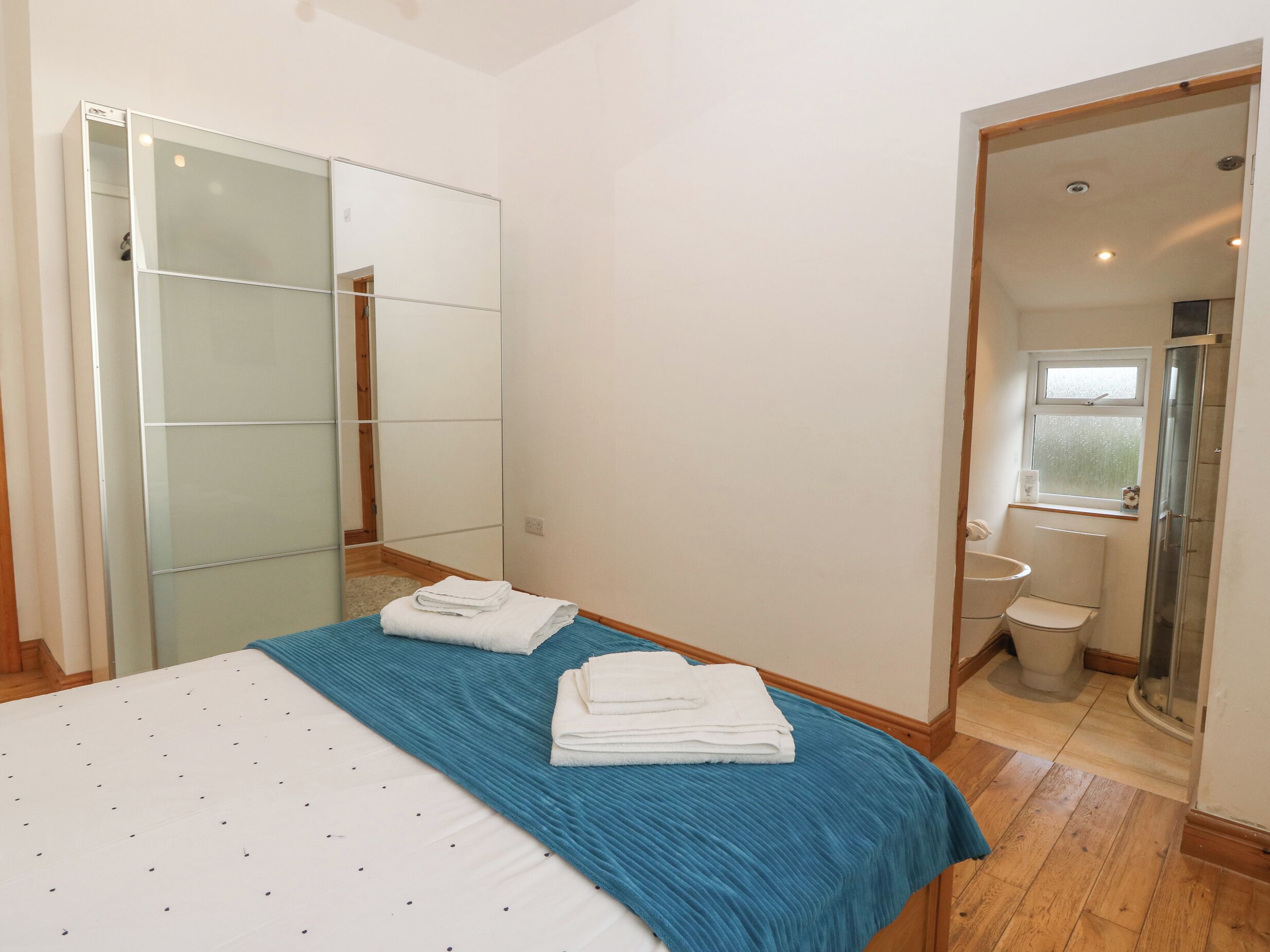 A bedroom with a bed, a blue bedspread, and a mirror.