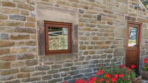 A stone building with two wooden doors and windows. - The Old Cart House (Hope Valley)