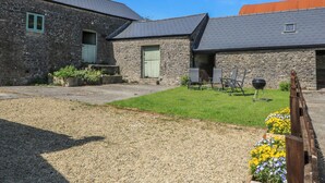 A stone building with a gravel driveway, a grassy lawn, and outdoor seating. - Dale Barton (Wells)