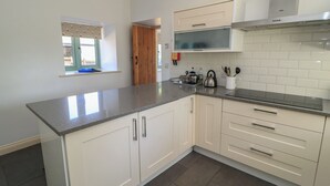 A kitchen with white cabinets, a granite countertop, and a window with a view. - Dale Barton (Wells)
