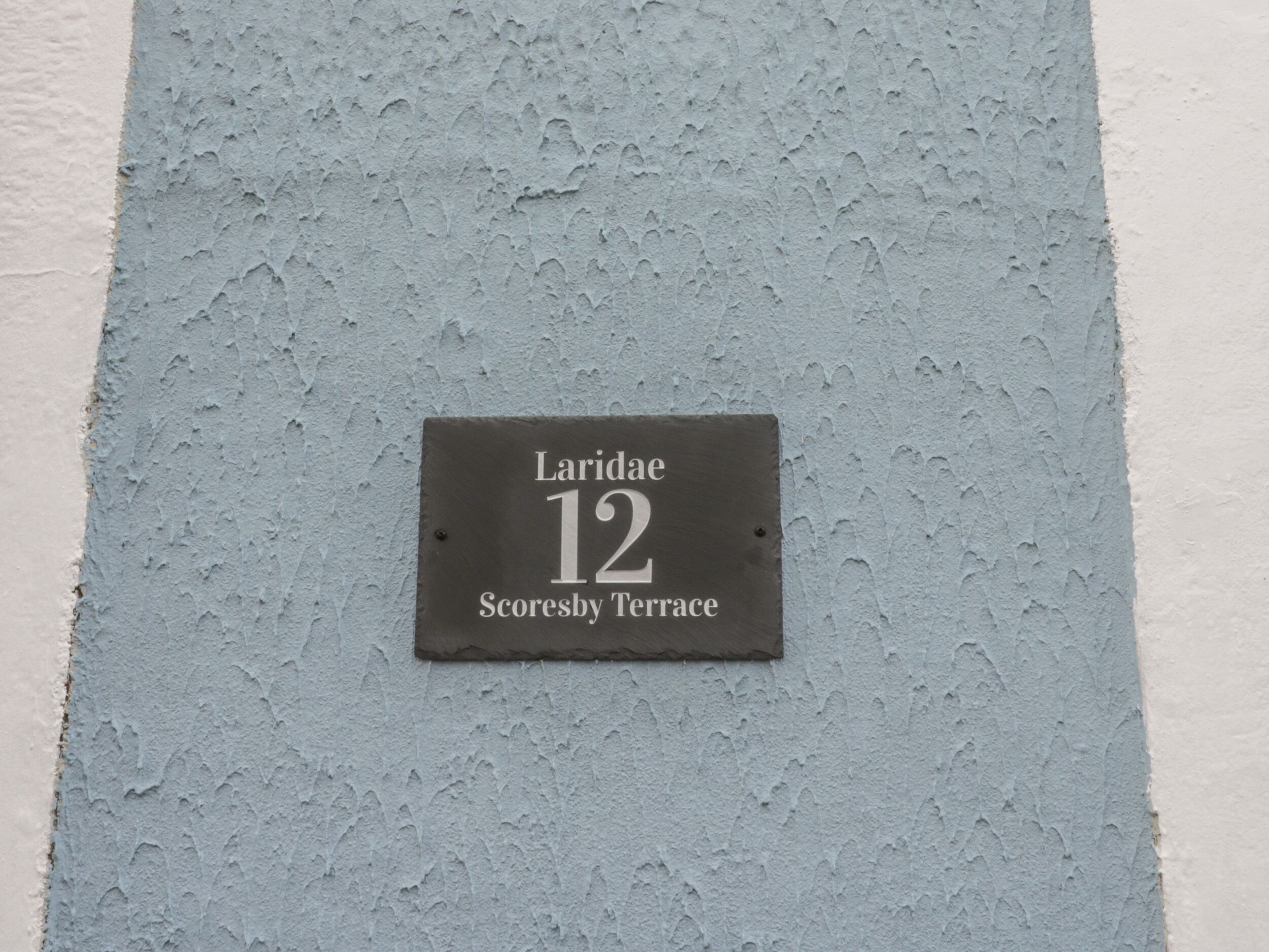 A house number sign on a textured wall.