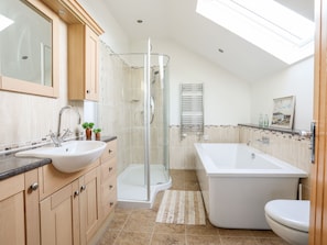 A modern bathroom with a walk-in shower, a freestanding bathtub, a sink with a mirror, and a toilet. - Gwelfor Barn (Beaumaris)