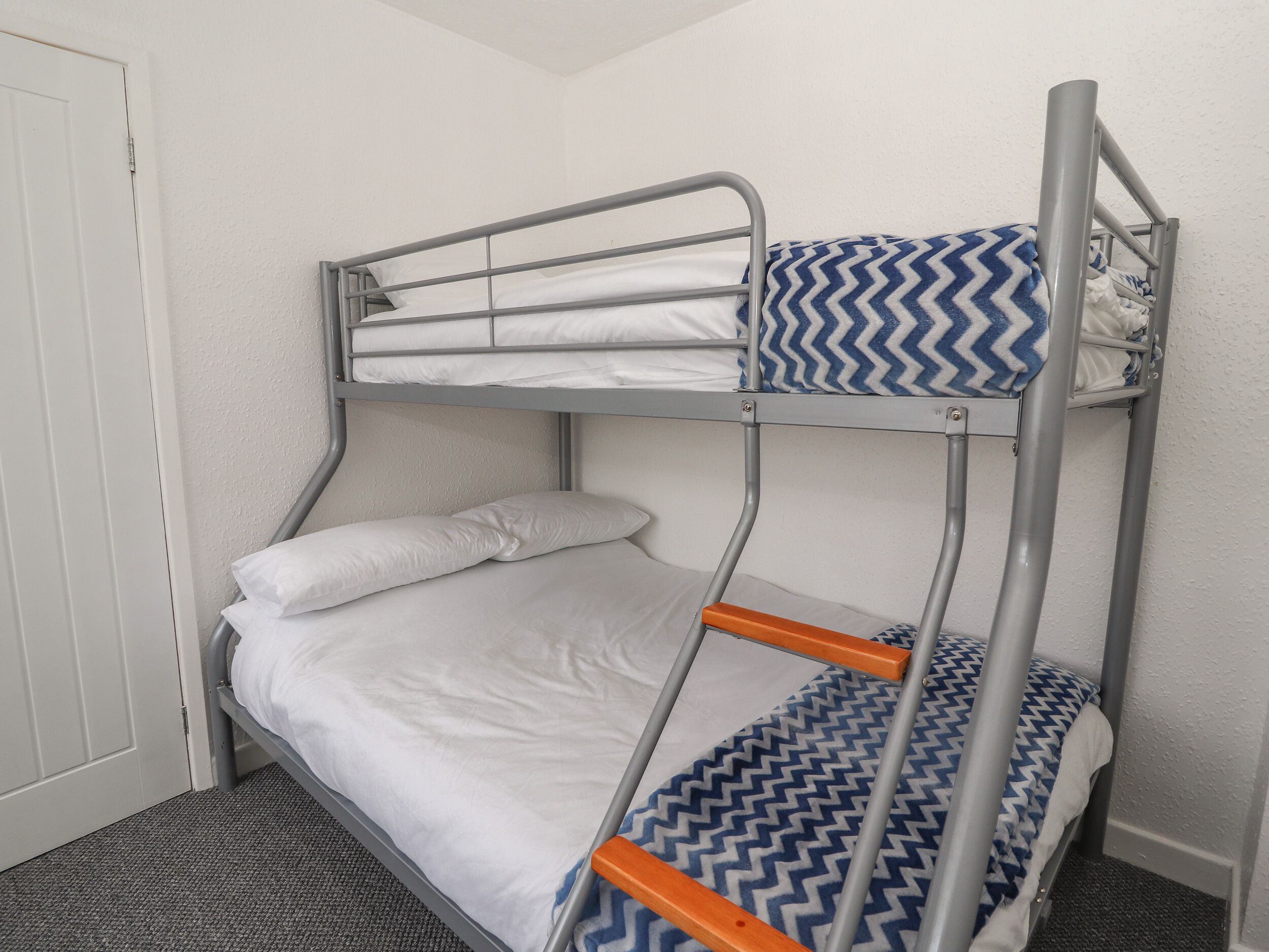 A bunk bed with a blue and white patterned bedspread, white pillows, and a grey metal frame.