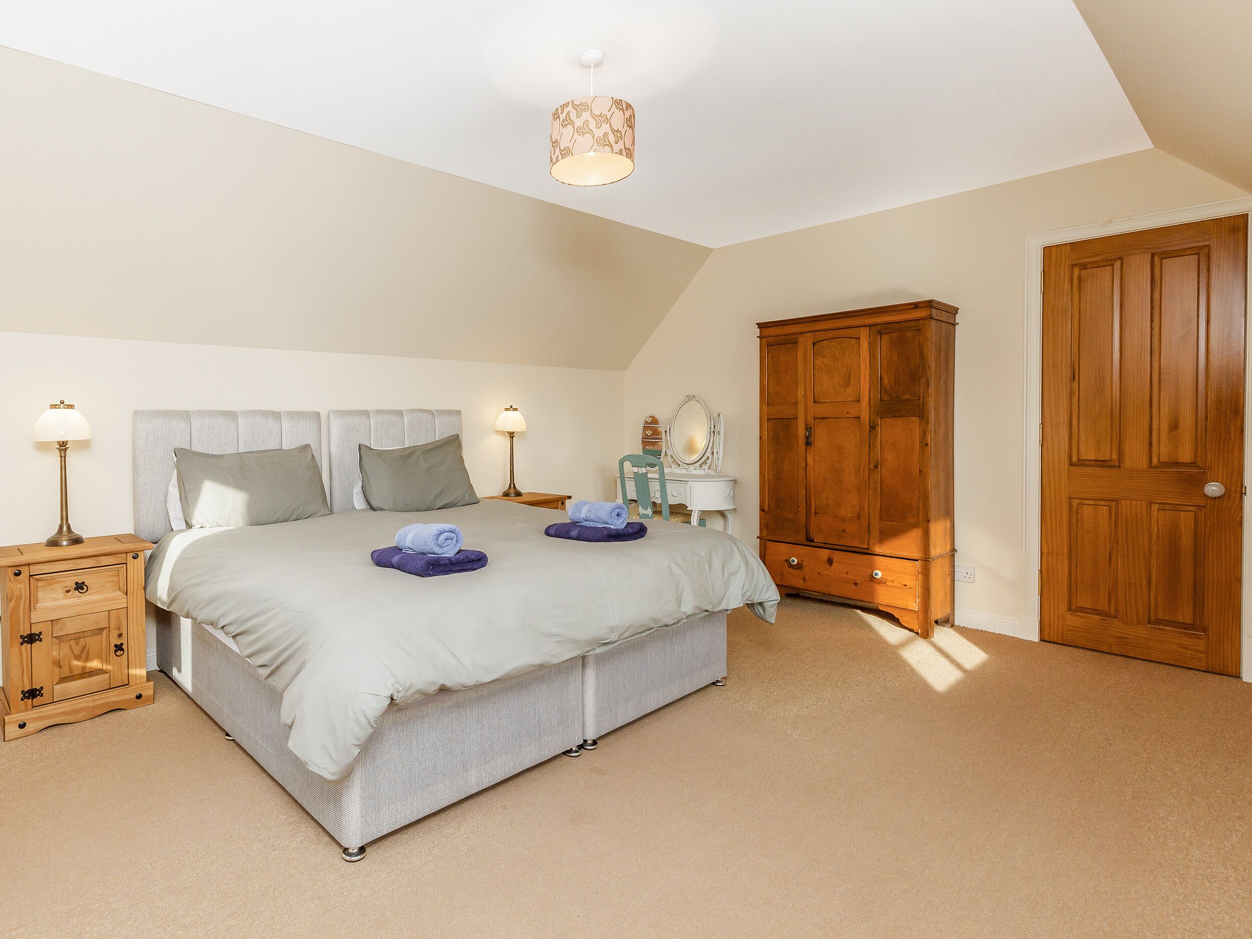 A bedroom with a bed, bedside tables, a wardrobe, and a mirror.
