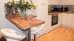 A modern kitchen with white cabinets, a wooden countertop, and a built-in oven. - Swale Cottage (Chathill)