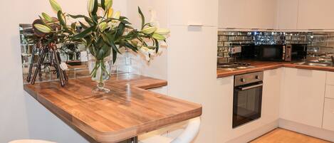 A modern kitchen with white cabinets, a wooden countertop, and a built-in oven.