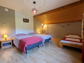 Une pièce chaleureuse avec deux lits, un plafond en bois et un luminaire suspendu.