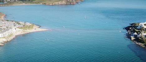 A coastal area with a sandy beach, a small harbor, and a few boats.