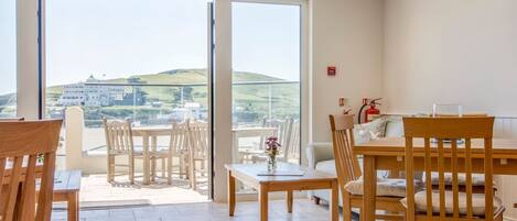 A hotel room with a balcony, wooden furniture, and a view of the countryside.