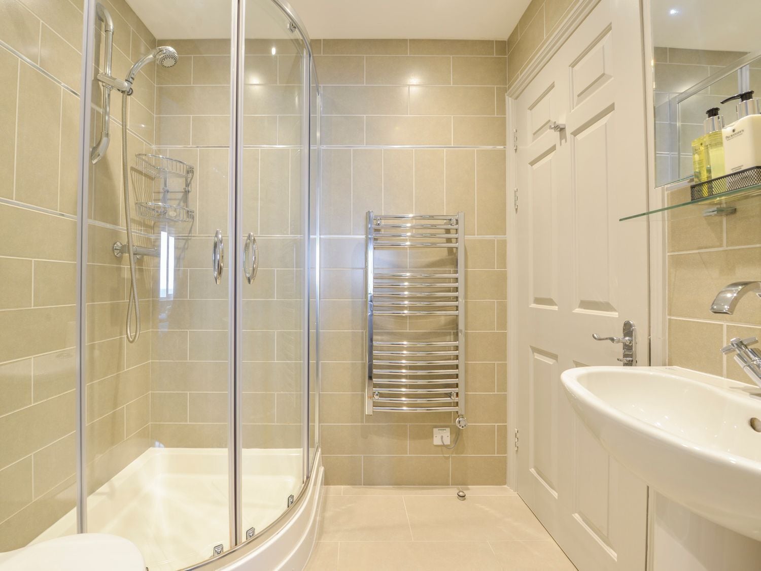 Een moderne badkamer met een douchecabine van glas, een bad, een inbouwwastafel en een handdoekhouder.