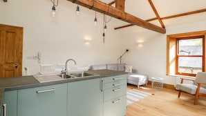 Una cocina con lavamanos integrado, un comedor con sofá y una ventana con vistas al exterior.