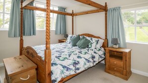 A four-poster bed with a floral bedspread, wooden nightstands, and a small wooden chest of drawers. - Fell Foot (Holmrook)