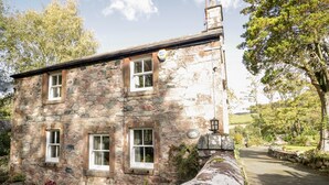 A stone building with multiple windows and a small garden area with potted plants. - Fell Foot (Holmrook)