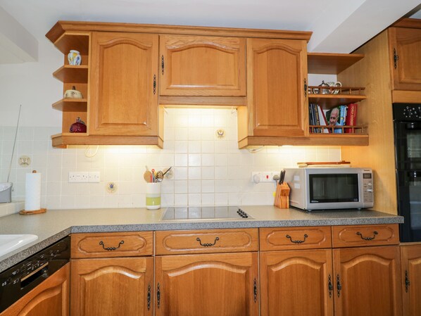 A kitchen with wooden cabinets, a microwave, and a dish rack.