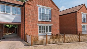 A two-story brick house with a front entrance, a small porch, and a wooden fence. - 26 Burtons Mill (Norwich)