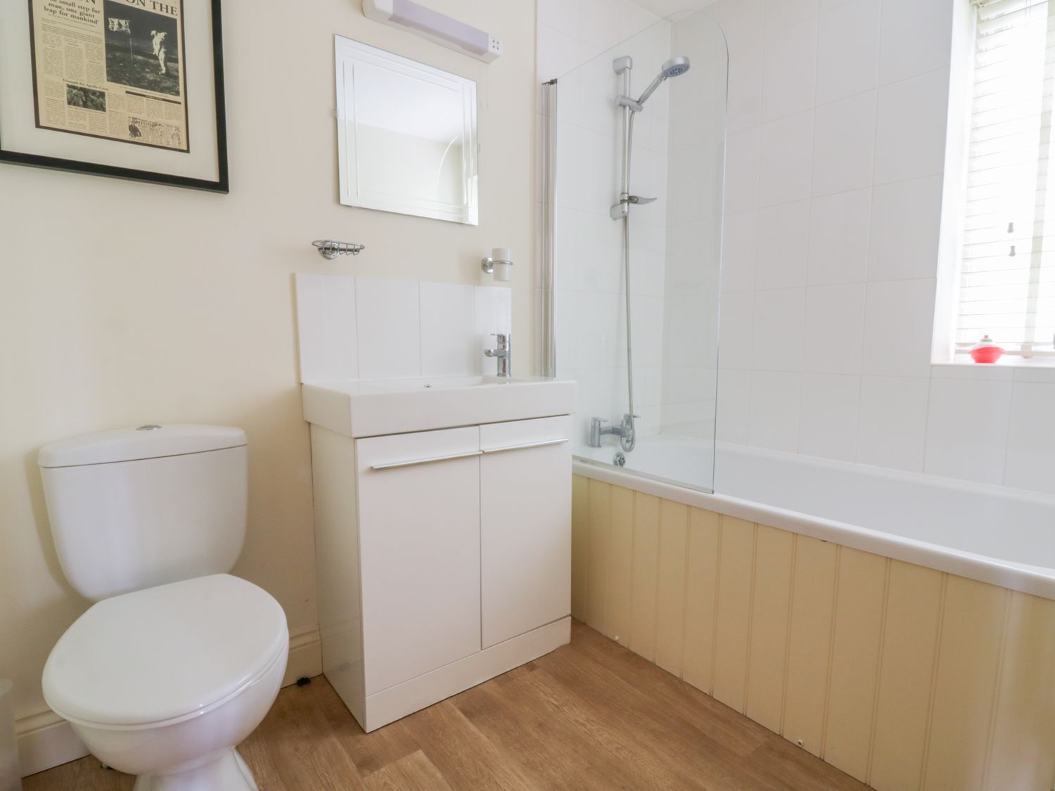 Un baño con inodoro, lavamanos con espejo y ducha.
