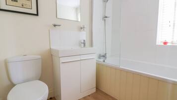 Un baño con inodoro, lavamanos con espejo y ducha.