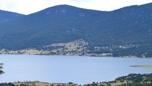 Un lago rodeado de colinas, con un pequeño pueblo al fondo.