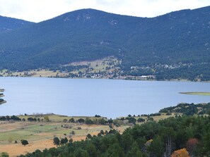 Um lago rodeado por colinas, com uma pequena cidade ao fundo.
