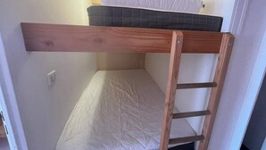 Una cama litera con escalera de madera y un colchón.