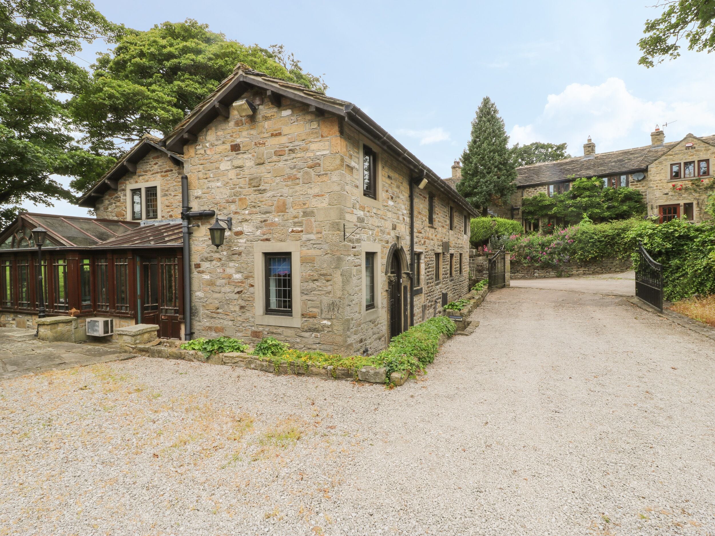 A stone building with a gravel driveway, wooden shutters, and a small garden area.