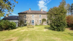 A stone building with a grassy yard and a wooden bench. - Ballintlea (Knockanroe)