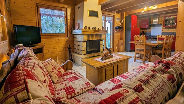 A cozy cabin interior with a fireplace, wooden furniture, and a television. - Comfortable chalet in Cleurie with WIFI, fireplace, and terrace (Cleurie)