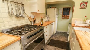 Eine Küche mit Gasherd, Backofen und verschiedenen Küchenutensilien an der Wand.
