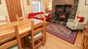 Ein gemütliches Wohnzimmer mit Kamin aus Stein, einem roten Sofa, einem Holzespeise-Tisch und einem gemusterten Teppich.